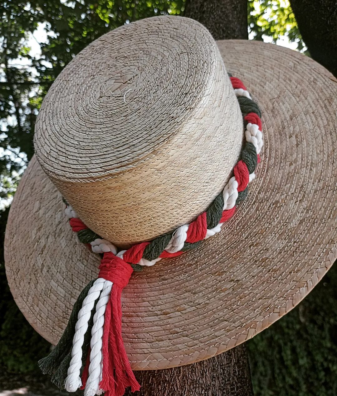 Sombrero de palma de ala plana cordones de algodón en rojo, blanco y verde.